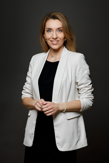 Man with curly hair wearing a brown ribbed turtleneck sweater against a beige background.