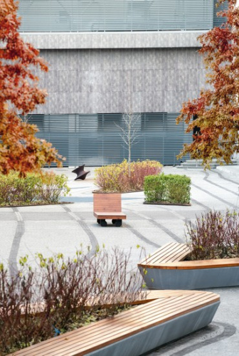 Curved rust-colored architectural walls with horizontal ridges under a clear blue sky.